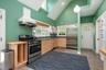 Kitchen with stainless steel appliances, custom range hood, light brown cabinetry, stone finish floors, and butcher block countertops