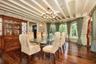 Dining area featuring wallpapered walls, a chandelier, hardwood / wood-style flooring, beam ceiling, and wainscoting