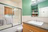 Bathroom featuring tile walls, vanity, combined bath / shower with glass door, and wainscoting