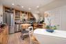 Kitchen with appliances with stainless steel finishes, light wood-style floors, glass insert cabinets, recessed lighting, and backsplash