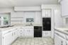 Kitchen with black appliances, a warming drawer, a sink, and light countertops