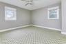 Spare room featuring healthy amount of natural light, carpet flooring, a ceiling fan, and baseboards