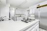 Kitchen featuring stainless steel refrigerator, a sink, washing machine and dryer, and white gas stovetop