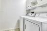Laundry room with washing machine and dryer, cabinet space, light tile patterned flooring, and baseboards
