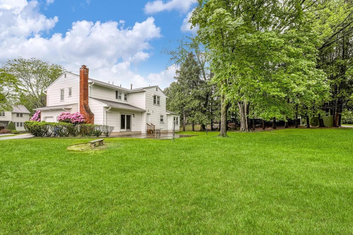 View of green lawn featuring a patio area and an attached garage