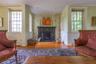 Living room featuring wood finished floors, healthy amount of natural light, a fireplace, ornamental molding, and a wainscoted wall