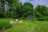 View of grassy yard featuring an outdoor fire pit, a patio, and a storage unit