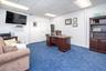 Home office with a drop ceiling and dark colored carpet