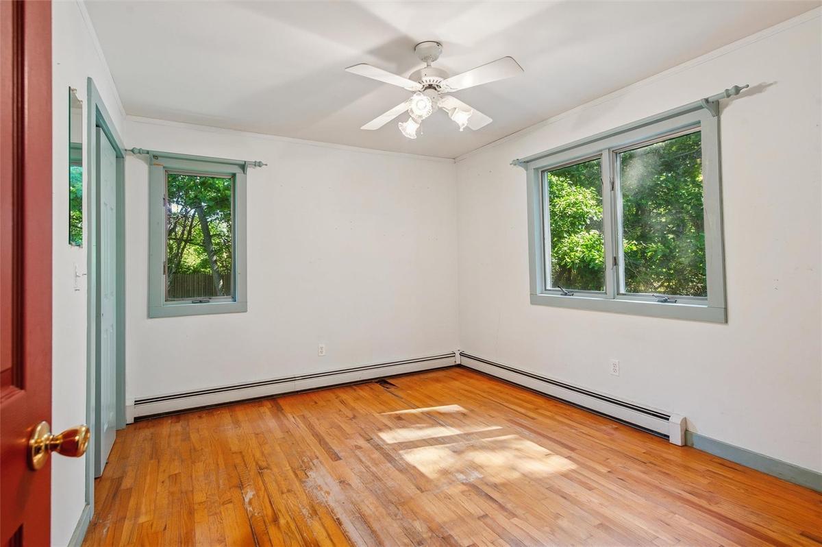 Unfurnished room with a baseboard heating unit, light wood-style floors, and ceiling fan