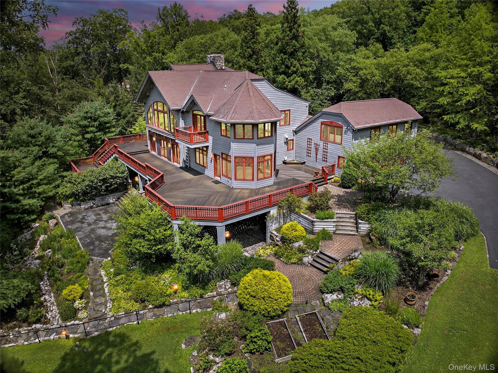 Back of property at dusk with a balcony, stairs, a wooden deck, roof with shingles, and a chimney