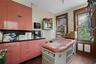 Kitchen with red cabinets, a sink, wood finished floors, and dark countertops