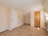 Additional living space featuring light wood finished floors, a baseboard radiator, vaulted ceiling, and an AC wall unit