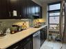 Kitchen with stainless steel dishwasher, dark cabinets, backsplash, and light stone counters
