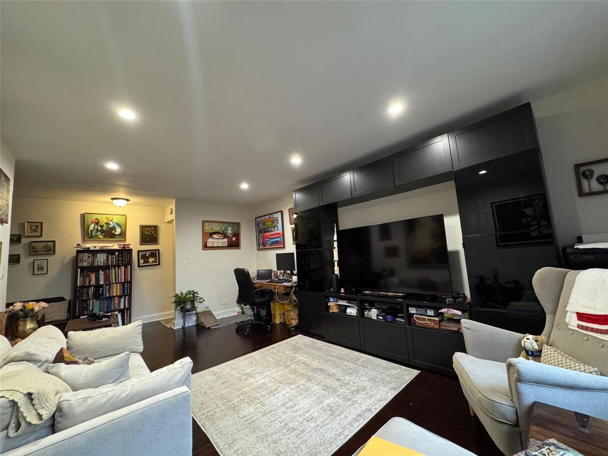 Living room with dark wood finished floors, recessed lighting, and a desk