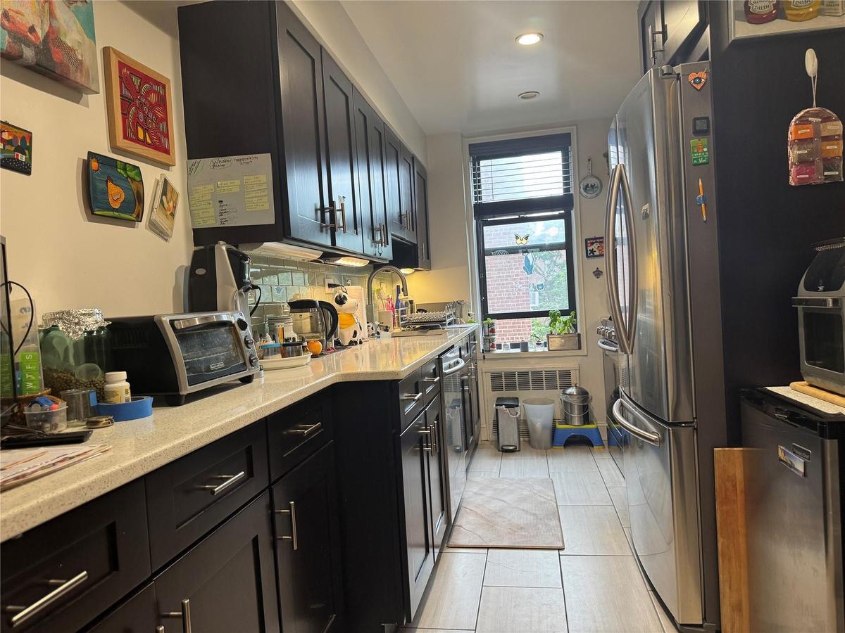 Kitchen with freestanding refrigerator, dark cabinetry, recessed lighting, and fridge