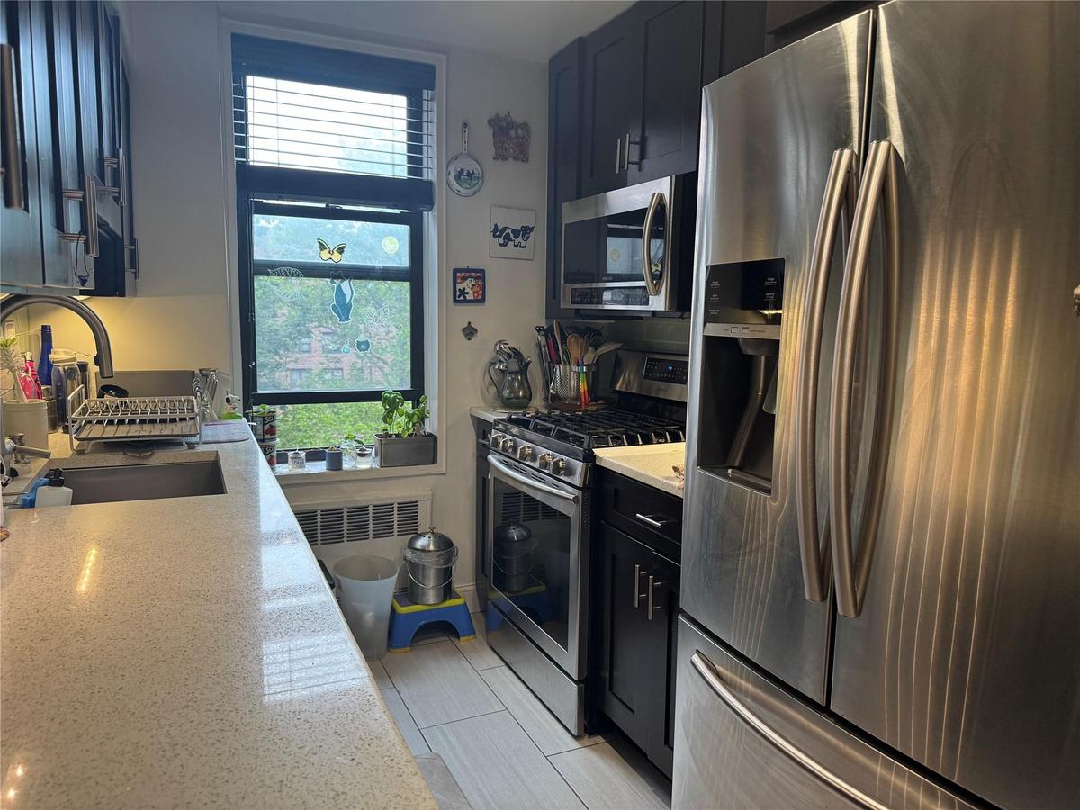 Kitchen with stainless steel appliances, light countertops, and dark cabinetry