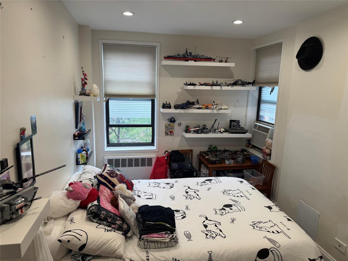 Bedroom with radiator, multiple windows, cooling unit, and recessed lighting