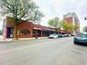 View of asphalt street featuring sidewalks, curbs, and street lights
