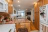 Kitchen featuring white appliances, a peninsula, recessed lighting, light stone countertops, and brown cabinetry
