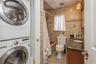 Bathroom featuring estacked washer and dryer, tile walls, tiled shower / bath combo, vanity, and tile patterned flooring