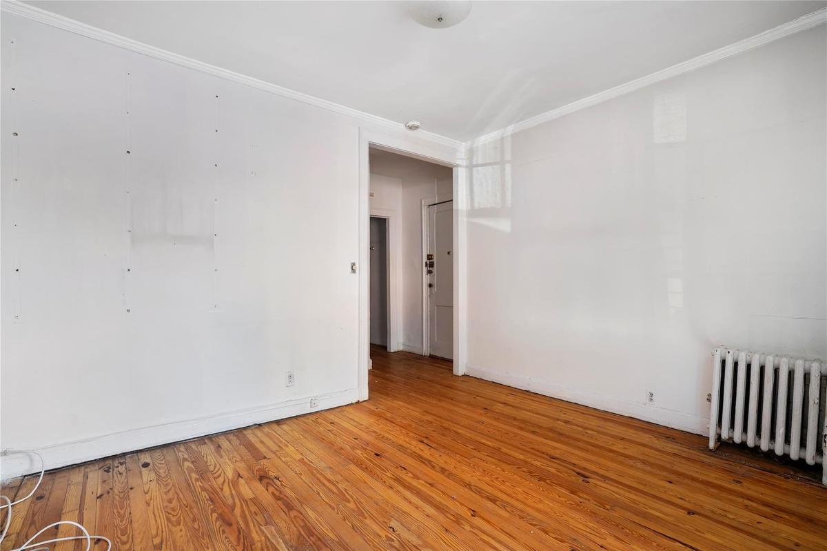 Unfurnished room with radiator heating unit, crown molding, and hardwood / wood-style floors