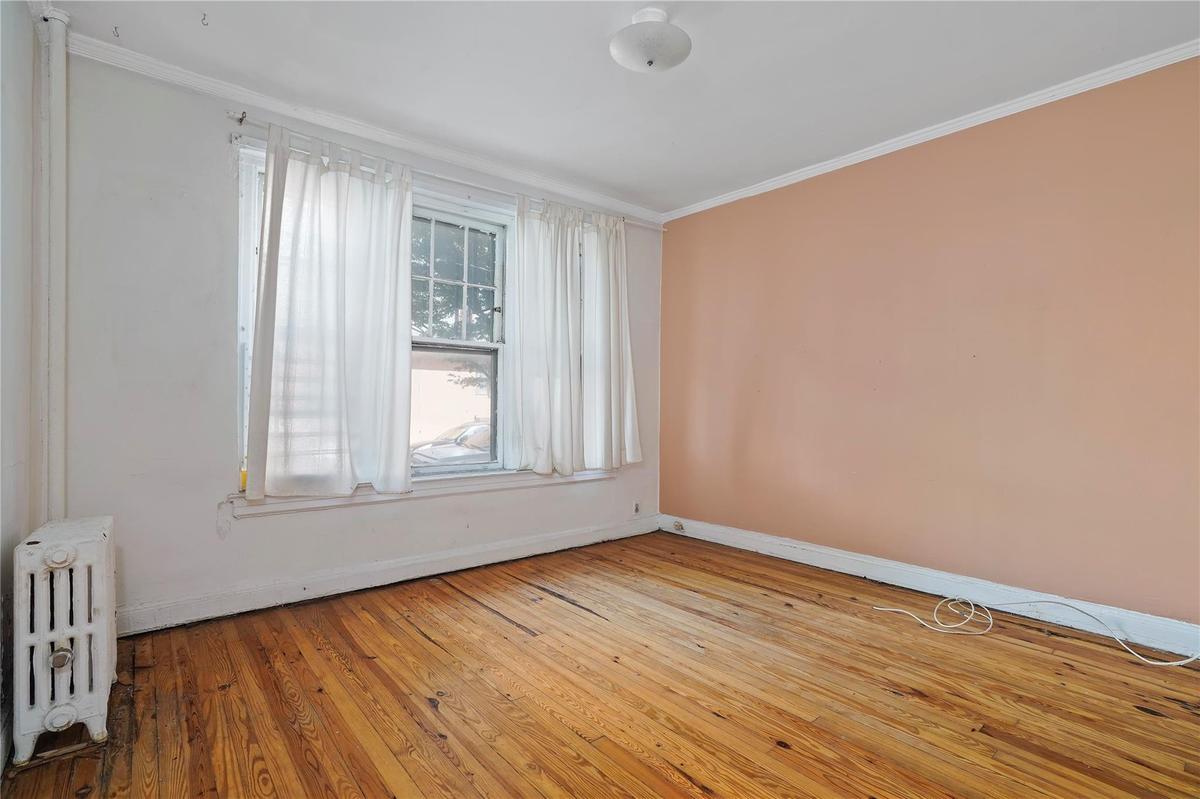 Empty room featuring radiator heating unit, crown molding, and hardwood / wood-style flooring