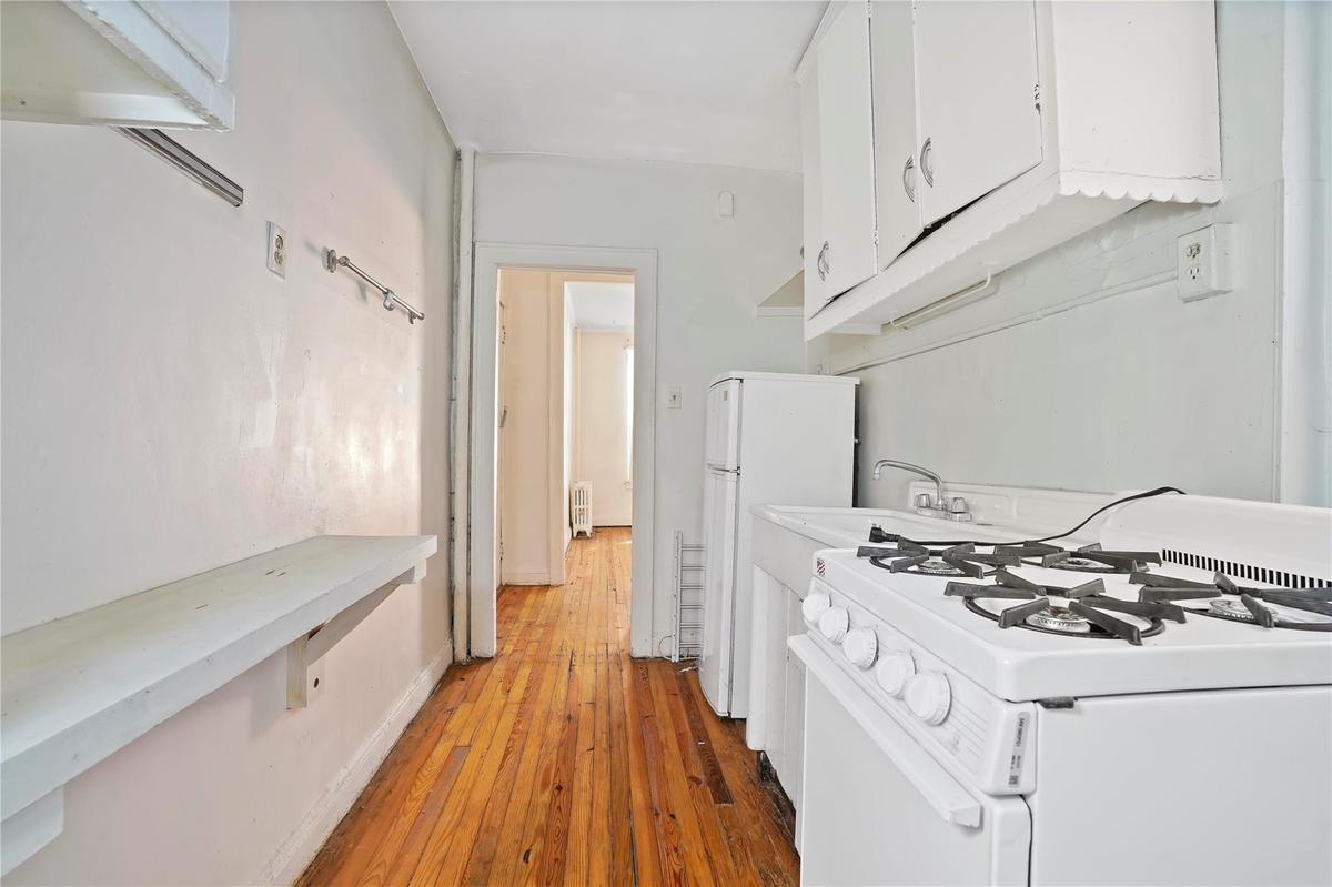 Kitchen with white appliances, white cabinetry, light wood-style flooring, and light countertops
