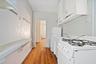 Kitchen with white appliances, white cabinetry, light wood-style flooring, and light countertops