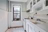 Kitchen featuring white gas stove, white cabinetry, light floors, light countertops, and glass insert cabinets