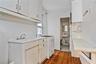 Kitchen with white gas stove, dark wood-style floors, light countertops, and white cabinets