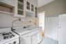 Kitchen with white appliances, light flooring, white cabinets, and light countertops