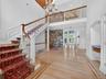Stairway with a chandelier, a towering ceiling, a decorative wall, wood finished floors, and arched walkways