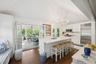 Kitchen featuring stainless steel appliances, a chandelier, dark wood-style floors, white cabinetry, and an island with sink