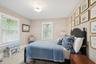 Bedroom with multiple windows, wallpapered walls, and wood finished floors