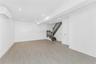 Finished below grade area featuring an AC wall unit, light wood-style flooring, stairs, and recessed lighting