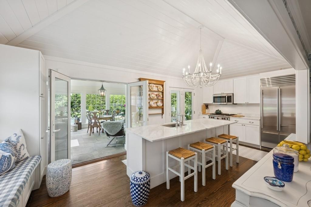 Kitchen featuring stainless steel appliances, a chandelier, dark wood-type flooring, white cabinetry, and an island with sink