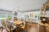 Dining room with dark wood-type flooring, a chandelier, ornamental molding, wallpapered walls, and wainscoting