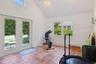 Pool house. Workout area with light tile patterned flooring, high vaulted ceiling, a wainscoted wall, and french doors