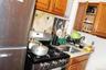 Kitchen with fridge, stainless steel gas stove, brown cabinets, and light countertops