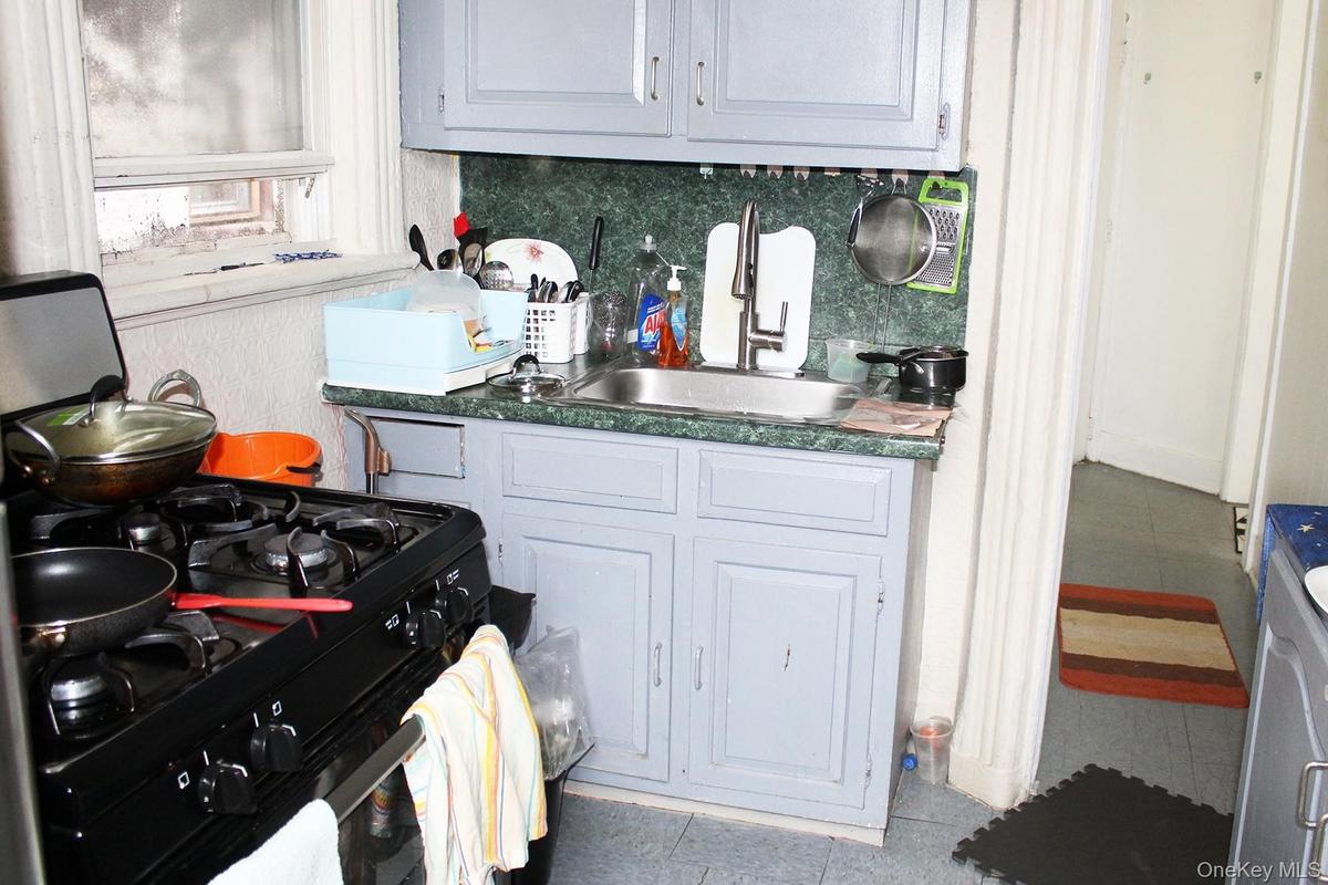 Kitchen featuring black gas stove, white cabinets, backsplash, tile patterned flooring, and washer / clothes dryer