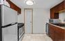 Kitchen featuring appliances with stainless steel finishes, light tile patterned floors, light stone countertops, and beverage cooler