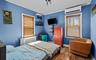 Bedroom featuring wood finished floors, a wall unit AC, radiator heating unit, and ornamental molding