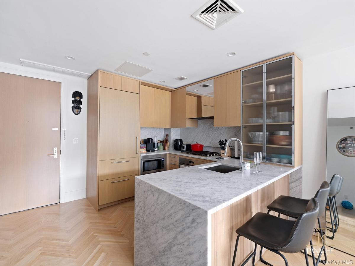 Kitchen featuring light brown cabinets, a kitchen breakfast bar, decorative backsplash, modern cabinets, and a peninsula