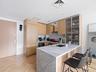 Kitchen featuring light brown cabinets, a kitchen breakfast bar, decorative backsplash, modern cabinets, and a peninsula