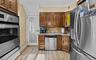 Kitchen featuring appliances with stainless steel finishes, decorative backsplash, light wood finished floors, ornamental molding, and a warming drawe