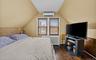 Bedroom featuring radiator heating unit, dark wood-type flooring, lofted ceiling, and an AC wall unit