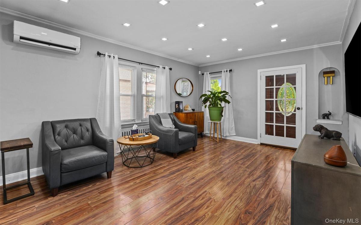 Sitting room featuring wood finished floors, crown molding, an AC wall unit, and recessed lighting
