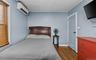 Bedroom with dark wood-style floors, an AC wall unit, and ornamental molding