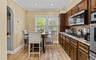 Kitchen featuring light wood-style floors, arched walkways, crown molding, light stone countertops, and stainless steel appliances