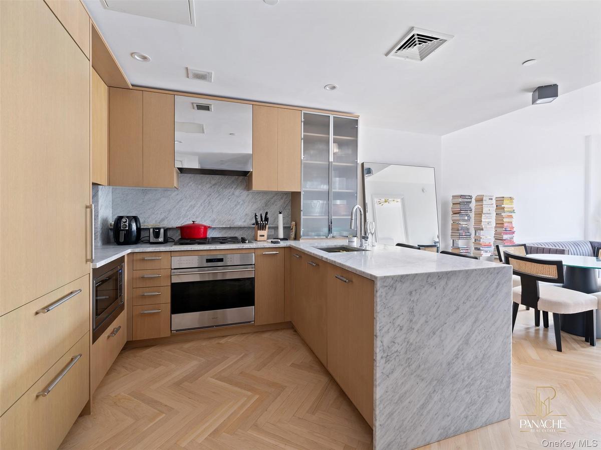 Kitchen with a peninsula, light brown cabinets, modern cabinets, and recessed lighting